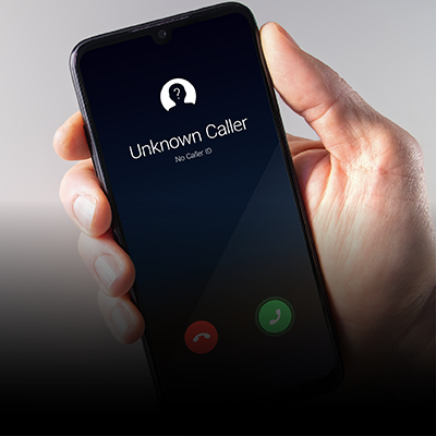 A hand holding a phone with an Unknown Caller on the screen