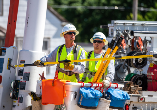 Two Evergy linemen perform work on utility lines